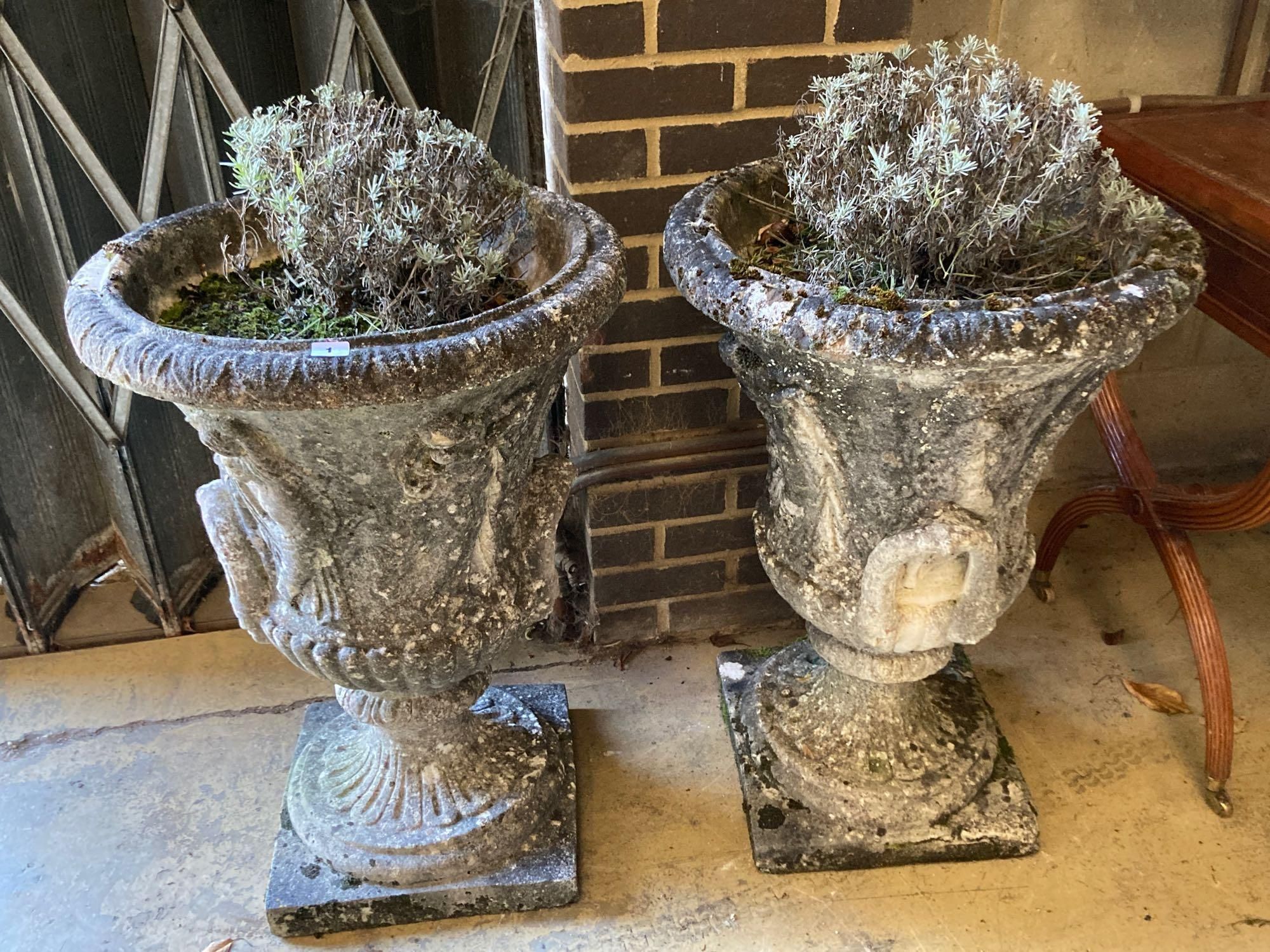 A pair of weathered composition stone urns and pedestals, diameter 56cm height 81cm